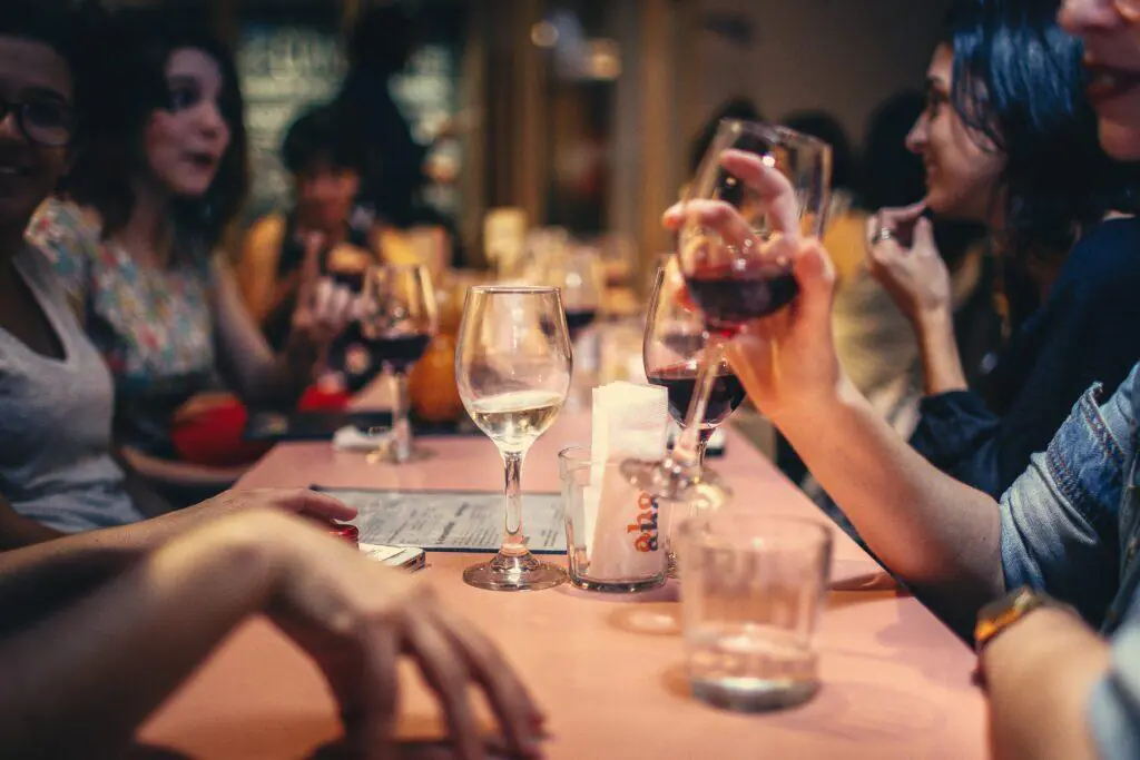 Group of women enjoying a wine tasting event, with glasses of red and white wine on a table. This image captures the social and sophisticated nature of wine tasting, a popular feminine hobby.