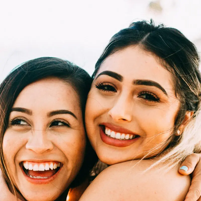 Two smiling women hugging, showcasing their close friendship with bright expressions, perfect for illustrating a blog post about friendship captions for Instagram.